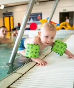 Kleiner Junge mit Schwimmflügeln am Pool